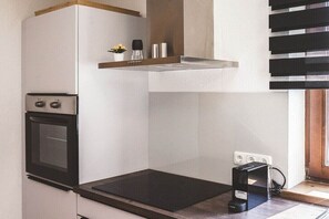 Eine kleine Küche mit eingebautem Backofen, einem Kochfeld und einer Arbeitsplatte.