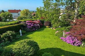 Un jardin bien entretenu, agrémenté d’une statue, de haies taillées avec soin et de plantes en fleurs.