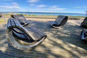 Eine Holzterrasse mit Liegestühlen, die auf ein Gewässer ausgerichtet ist.