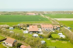 Ein ländliches Anwesen mit mehreren Gebäuden, darunter ein großes Haus mit rotem Dach, kleinere Bauten und ein Feld.