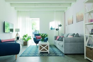 Ein Wohnzimmer mit einer Couch, einem Sessel, einem Couchtisch und einem Bücherregal.