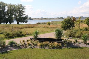 A landscaped area with a pathway, a boat-shaped planter, and a body of water in the background. - Holiday home in Mellnitz with swimming pool (Mellnitz)