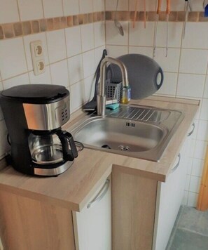 Eine Küche mit Kaffeemaschine, Spüle und einer Hängevorrichtung für Küchenutensilien.