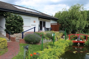 Ein Haus mit Garten, Teich und roter Brücke.