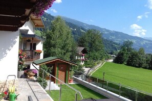 Ein Balkon mit Blick auf einen Berg, einer Holzkonstruktion und einer grünen Rasenfläche.