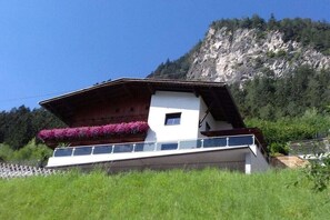 Ein Chalet mit Balkon, kleinem Fenster und Bergblick.