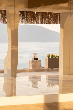 A modern interior with a large window overlooking a body of water and a mountain.