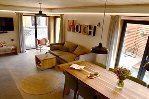Ein modernes Wohnzimmer mit einer Couch, einem Esstisch und einem Fernseher.
