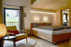 Ein Schlafzimmer mit einem hölzernen Bett, Nachttischen, einem Sessel, einer Lampe und einem Fenster mit Vorhängen.
