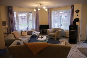 Ein Wohnzimmer mit einer Sofagarnitur, einem Couchtisch, einem Fernseher und einem Kamin.
