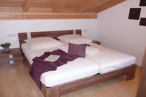 Ein Einzelbett mit Holz-Kopfteil, ein Nachttisch und ein Beistelltisch mit Lampe.
