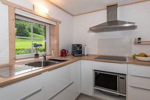 Eine moderne Küche mit Fenster, Edelstahlgeräten und Blick ins Grüne.
