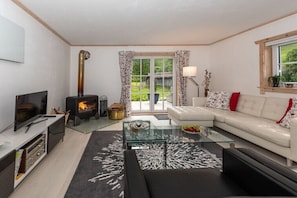 Ein Wohnzimmer mit Kamin, einer Couch, einem Glastisch und einem Fernseher.