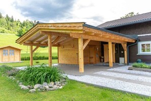 Eine Holzhütte mit überdachter Veranda, einer Schotterzufahrt und einem kleinen Nebengebäude.