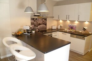 A modern kitchen with a central island, white cabinets, and pendant lighting. - Apartment Seezeichen in the Baltic Sea resort of Prerow (Ostseebad Prerow)