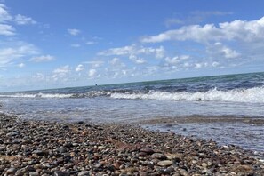 A pebbled beach with waves, clear sky, and distant horizon. - Apartment Seezeichen in the Baltic Sea resort of Prerow (Ostseebad Prerow)