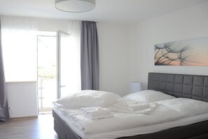 Ein ordentlich bezogenes Bett mit weißen Leinen und Kissen, ein grauer Kopfteil und ein Gemälde an der Wand.