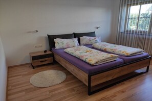Ein Schlafzimmer mit einem Bett, einem Nachttisch, einem runden Teppich und einem Fenster mit Vorhängen.