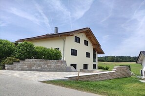 Ein zweigeschossiges Haus mit einem geneigten Dach, einer Steintreppe und einem gepflasterten Auffahrt.