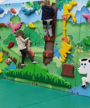 Kinder erklimmen eine bunte Spielkonstruktion mit verschiedenen Tierfiguren.