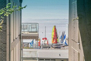 Blick auf Segelboote mit Flaggen auf einem Gewässer, aufgenommen von einem Gebäude mit Balkon.