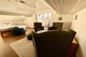 A loft bedroom with a bed, two chairs, a bean bag, and a view of the outdoors. - Waltenberger Sonthofen (Sonthofen)