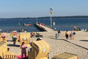 Ein Strand mit Liegestühlen, einem Steg und einer Flagge.