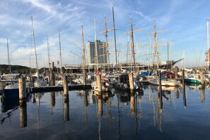 Ein Yachthafen mit mehreren dort angestuerten Booten, Holzpfählen und einem Gebäude im Hintergrund.