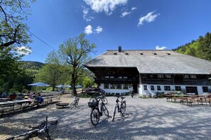 Ein Gebäude mit einem geneigten Dach, Außenbereich mit Sitzgelegenheiten und Fahrrädern davor.