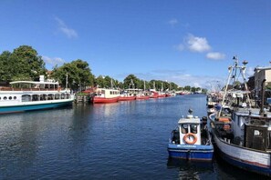 Ein Hafen mit vertäuten Booten entlang des Kanals, ein kleines Boot mit Rettungsring und ein Gebäude mit der Aufschrift 'Hafentour'.