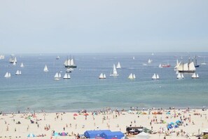 Een strand met vele zeilboten en een druk zandgebied.