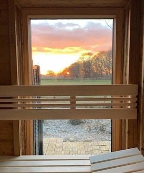 A wooden-framed window with a view of a sunset over a grassy field. - Holiday home Lüttes Paradies (Geestland)
