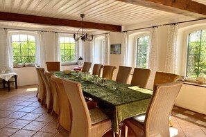 Ein Esszimmer mit einem langen Tisch, Korbstühlen und einem Kronleuchter.