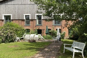 Ein Backsteinhaus mit Garten-Terrasse, Außenbestuhlung und einem Weg zum Eingang.