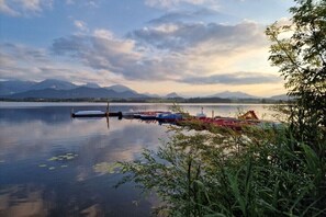 Ein ruhiger See mit anlegenden Booten, umgeben von Bergen und Grünflächen.