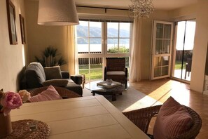 Ein geräumiges Wohnzimmer mit großem Fenster, Essbereich und Seeblick.