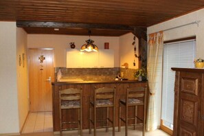 A kitchen with wooden bar stools, a tiled backsplash, and a hanging light fixture. - Holiday apartment with 1 bedroom (54347 Neumagen-Dhron, Deutschland)