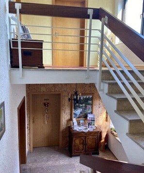 A multi-level interior with a staircase, a wooden cabinet with items, and a door with a key. - Holiday apartment with 1 bedroom (54347 Neumagen-Dhron, Deutschland)