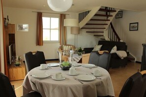 A dining area with a table set for four, a staircase, and a sofa in the background. - Holiday home in Zierow with swimming pool (Zierow)