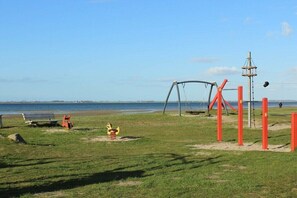 A park with a swing set, a bench, and a playground. - Holiday home in Zierow with swimming pool (Zierow)
