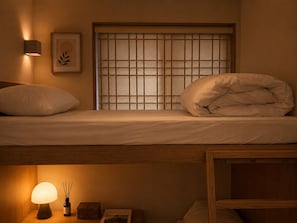 A bunk bed with a headboard, a bedside lamp, a framed picture, and a window with a grid pattern. - MellowStay Hongdae (Seoul)