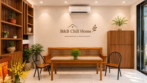 A B&B chill home with a wooden bench, chairs, a table, and a wall-mounted air conditioner. - B&B Chill Home (Ho Chi Minh City)