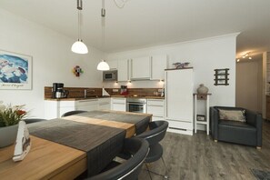 Eine moderne Küche mit weißen Schränken, einem Holzesstisch und schwarzen Stühlen.