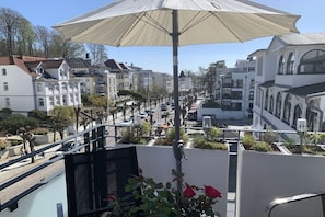 Straßenansicht mit Gebäuden, einer Straßenlaterne und einem großen Schirm.