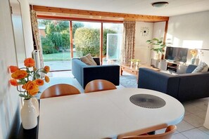 Ein modernes Wohnzimmer mit Esstisch, Sofas und Fernseher.