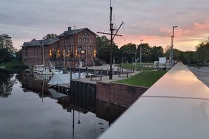 A waterfront building with a dock, a boat, and a grassy area. - Holiday apartment with 1 bedroom (Norden)