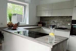 A modern kitchen with a built-in stove, a window, and a view of the outdoors. - Holiday apartment with 1 bedroom (Norden)