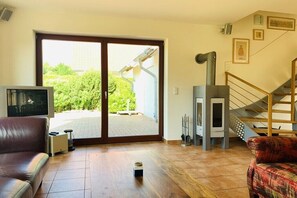 Ein Wohnzimmer mit einer Couch, einem Fernseher, einem Kamin und einer Treppe.
