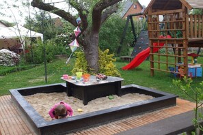 Ein Spielbereich für Kinder mit Sandkasten, Klettergerüsten und einer Rutsche.