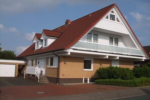 Ein zweistöckiges Haus mit rotem Ziegeldach, einer Veranda und einer Garage.
